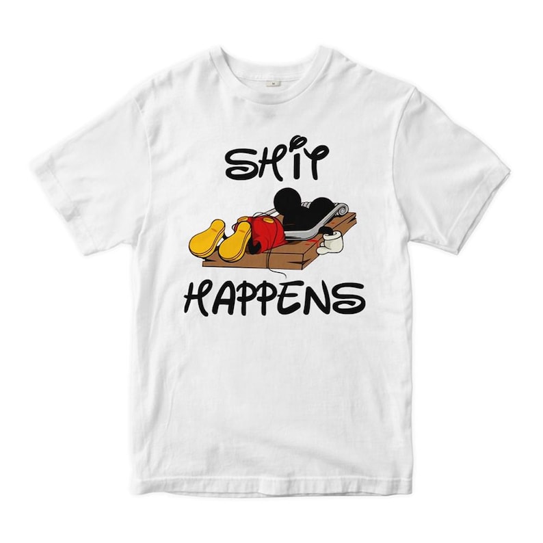 Puede incluir: Camiseta blanca con un personaje de dibujos animados negro y rojo atrapado en una trampa para ratones. El texto "SHIT HAPPENS" est&aacute; impreso en negro debajo del personaje.