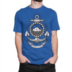 May include: A royal blue t-shirt with a white anchor graphic. The anchor is surrounded by a rope and waves. The text "Stay True" is written above the anchor and "Keeping it Real" is written below the anchor.