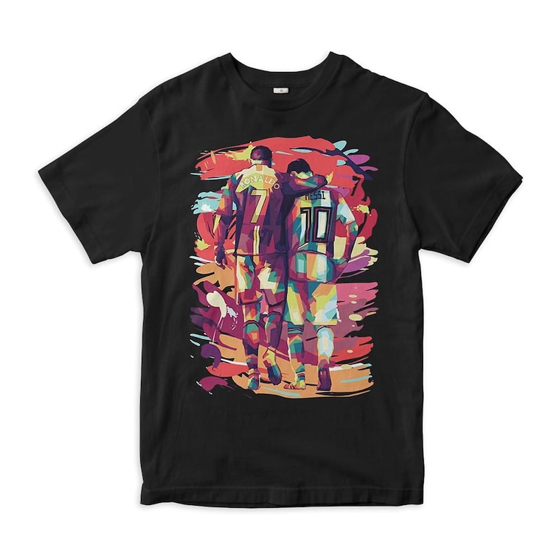 May include: Black t-shirt with a colorful graphic of two soccer players, Cristiano Ronaldo and Lionel Messi, walking side-by-side. The graphic is in a pop art style with bold colors and outlines.