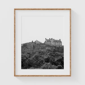May include: A black and white photograph of Edinburgh Castle perched atop a rocky hill. The castle is a historic fortress with a long and storied past.