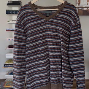 May include: A set of three ceramic mugs with a speckled, cream-colored glaze. Each mug features a different hand-painted floral design in shades of blue, green, and yellow. The mugs have a simple, rounded shape and a comfortable handle.