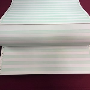 May include: A roll of continuous form paper with pale green horizontal lines and perforated edges. The paper is white with a light green stripe pattern. The paper is partially rolled, revealing the interior.