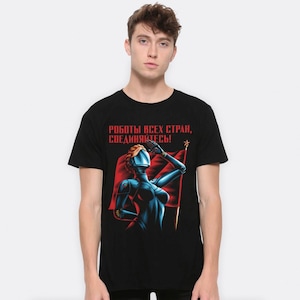 Könnte beinhalten: Ein schwarzes T-Shirt mit einem Grafikdruck einer Roboterfrau, die mit einer roten Flagge salutiert. Der Text auf dem Shirt lautet "роботы всех стран, соединяйтесь!"