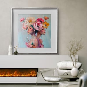 Puede incluir: Una pintura enmarcada de dos mujeres con flores en la cabeza. Las mujeres miran en direcciones opuestas y tienen una expresi&oacute;n suave y so&ntilde;adora. Las flores son rosas, blancas y amarillas. El fondo es azul claro.