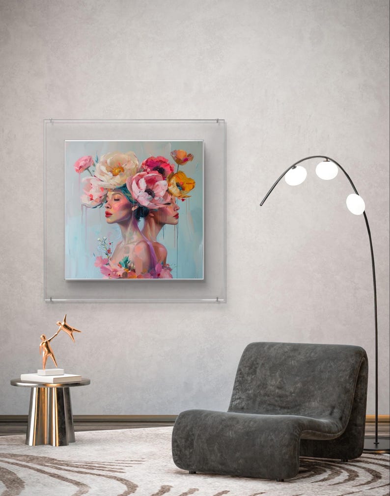 Puede incluir: Una pintura enmarcada de dos mujeres con flores en la cabeza. Las mujeres miran hacia adelante y las flores son rosas, blancas y amarillas. El fondo es de color azul claro.