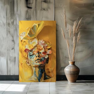 Op de afbeelding: Een schilderij van een gezicht met bloemen die de ogen bedekken. De achtergrond is geel en de bloemen zijn in verschillende kleuren, waaronder roze, geel en wit.