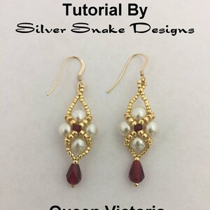 Puede incluir: Pendientes de oro con perlas blancas y cuentas rojas, etiquetados como "Queen Victoria Earrings". Los pendientes están hechos por Silver Snake Designs.