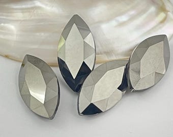 以下が含まれることがあります： 鏡のような反射面を持つ、メタリックシルバー色のマーキスカットのファセットストーン4個。各ストーンは、光を捉えて鋭いハイライトと深い影を作り出す、複数の幾何学的なファセットを備えた尖った細長い楕円形をしています。