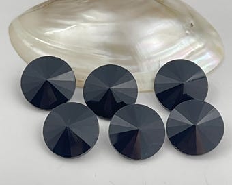 以下が含まれることがあります： ファセット加工された円錐形の表面を持つ5つの黒い円形ボタンのセット。各ボタンは中心点から放射状に伸びる線が特徴で、素材の暗く反射する表面に幾何学的な星のようなパターンを作り出しています。