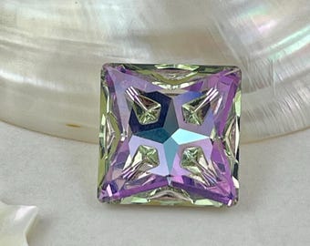 以下が含まれることがあります： プリンセスカットの正方形の、虹色の宝石。紫、緑、青など、さまざまな色が表示され、中央には星のような模様があります。宝石は真珠色の背景に置かれています。