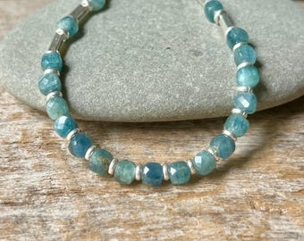 May include: A silver bracelet with blue gemstone beads. The bracelet is made with faceted beads and silver spacers.