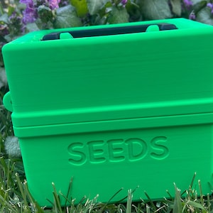 May include: A bright green plastic box with a black handle and the word "SEEDS" embossed on the front.