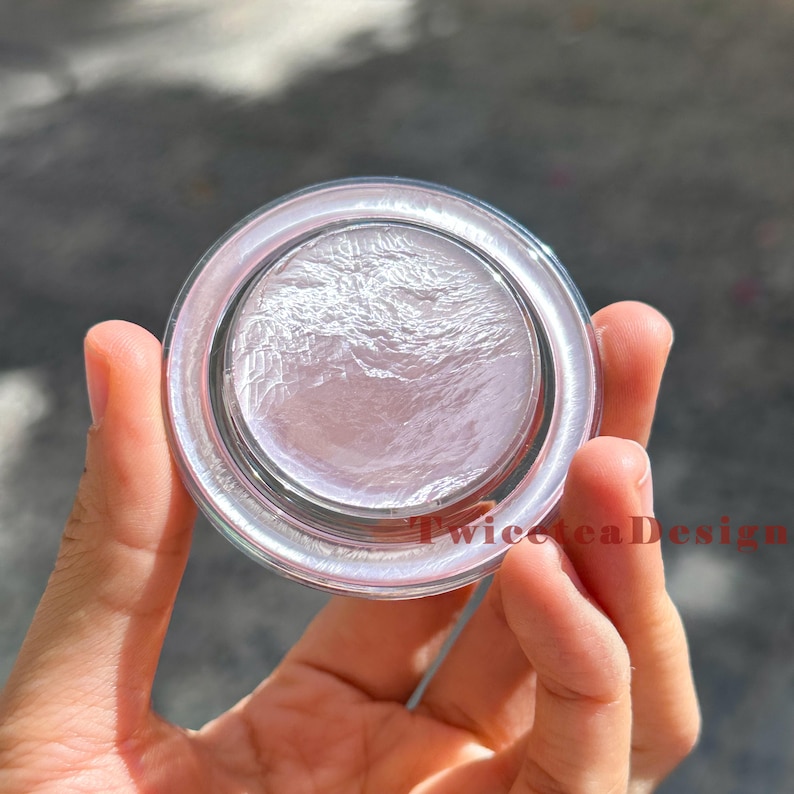 Może przedstawiać: Przezroczysty szklany słoik z perłową, jasno r&oacute;żową substancją w środku. Słoik ma szeroką, zaokrągloną krawędź i jest trzymany w dłoni. Tekst "TwiceteaDesign" jest widoczny w prawym dolnym rogu.