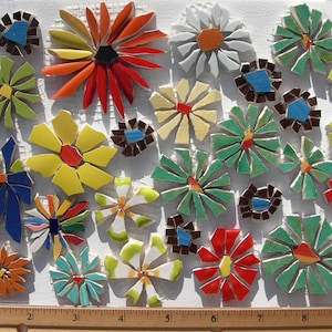 May include: A collection of colorful mosaic flower tiles in various sizes and designs. The flowers feature shades of red, orange, yellow, green, blue, and white. A ruler is at the bottom, showing measurements in inches.