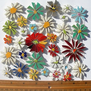 May include: A collection of mosaic flower tiles in various colors, including white, red, green, yellow, and blue. The flowers are arranged on a white mesh backing. A wooden ruler is at the bottom, showing measurements in inches.