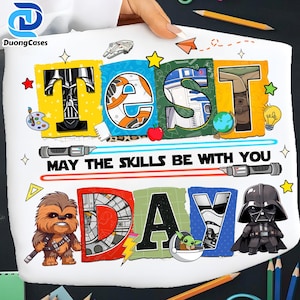May include: White t-shirt with a colorful "TEST DAY" design featuring Star Wars characters and elements. The phrase "MAY THE SKILLS BE WITH YOU" is printed below the word "TEST". Includes images of Darth Vader, Chewbacca, and R2-D2.