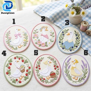 May include: Six circular embroidered patches featuring white geese in various scenes. Each patch is bordered in a different pastel color and depicts a goose with accessories like hats, scarves, or baskets, surrounded by floral, berry, or leaf wreaths.