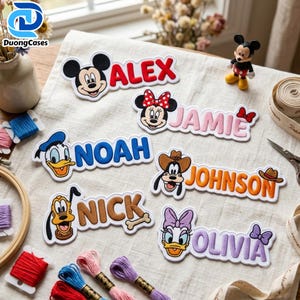May include: Six embroidered name patches featuring Disney characters: Mickey Mouse with red text ALEX, Minnie Mouse with pink text JAMIE, Donald Duck with blue text NOAH, Goofy with orange text JOHNSON, Pluto with brown text NICK, and Daisy Duck with purple text OLIVIA.