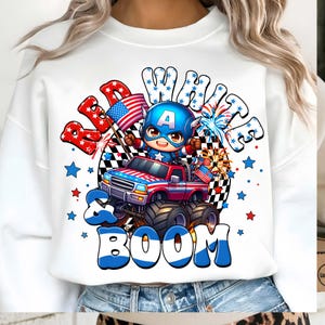 Puede incluir: Sudadera blanca con un gr&aacute;fico de dibujos animados de un superh&eacute;roe conduciendo un cami&oacute;n monstruo rojo, blanco y azul. El dise&ntilde;o incluye las palabras "Red, White & Boom" con estrellas y fuegos artificiales, celebrando el D&iacute;a de la Independencia.