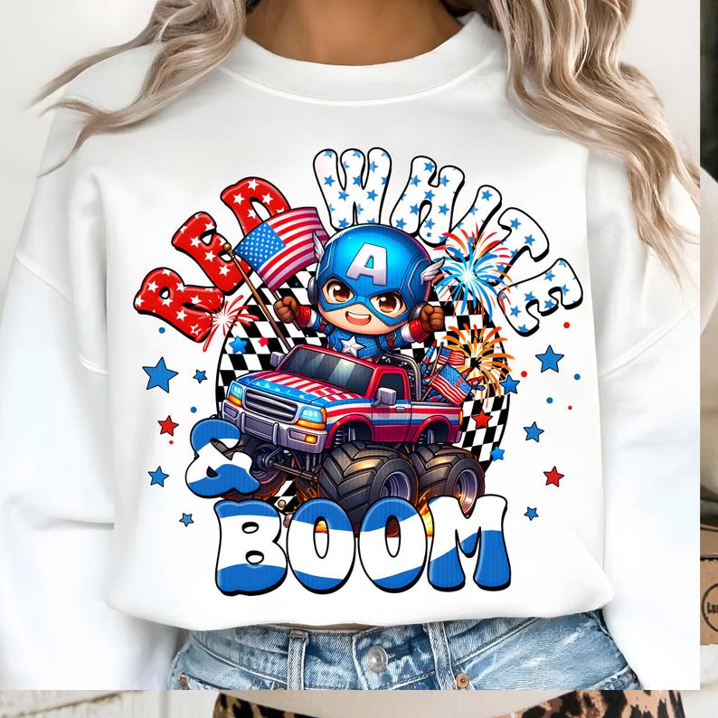Puede incluir: Sudadera blanca con un gr&aacute;fico de dibujos animados de un superh&eacute;roe conduciendo un cami&oacute;n monstruo rojo, blanco y azul. El dise&ntilde;o incluye las palabras "Red, White & Boom" con estrellas y fuegos artificiales, celebrando el D&iacute;a de la Independencia.