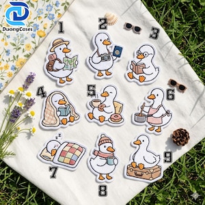 Peut inclure: Une collection de neuf écussons brodés représentant des canards blancs, numérotés de un à neuf, illustrant diverses activités comme voyager, lire, cuisiner, dormir et boire du café, tous avec des becs et des pattes orange.