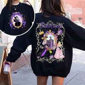 Puede incluir: Sudadera negra con una imagen enmarcada de Mal&eacute;fica en la parte delantera y trasera. El dise&ntilde;o trasero incluye la palabra "Mal&eacute;fica" en escritura p&uacute;rpura, una corona, un drag&oacute;n y una princesa con un vestido rosa. El dise&ntilde;o frontal es un primer plano de Mal&eacute;fica en un marco p&uacute;rpura.