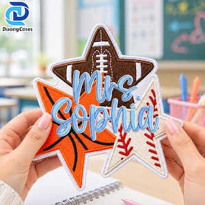 May include: A star-shaped embroidered patch featuring a brown football, an orange basketball, and a cream baseball with red stitching. The text Mrs. Sophia is embroidered in light blue script across the center of the three overlapping stars.