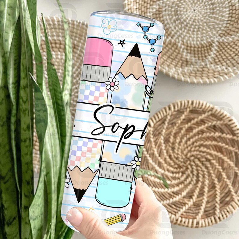 May include: A white tumbler with a pencil and eraser design, featuring the name "Sop" in black script. The design includes a pencil, eraser, flowers, and molecular structures. The tumbler is held by a person.