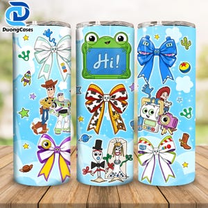 May include: Three cylindrical tumblers featuring a light blue background with Toy Story characters, including Woody, Buzz Lightyear, Forky, and Bo Peep. The design includes various colorful bows, a green frog-shaped frame with the text Hi!, and stars.