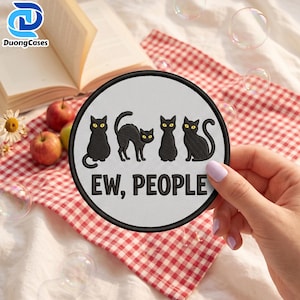 May include: A circular embroidered patch with a light gray background and a black border. The design features four black cats with yellow eyes in various poses above the black text that reads, "EW, PEOPLE" in a bold, sans-serif font.