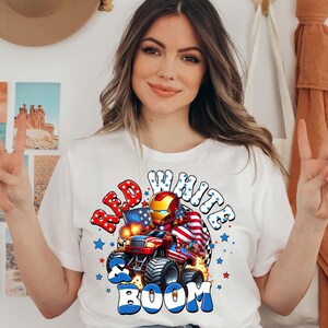 Puede incluir: Camiseta blanca con un gr&aacute;fico de un monstruo cami&oacute;n rojo, blanco y azul con un casco de Iron Man, una bandera estadounidense y las palabras "Red, White & Boom."