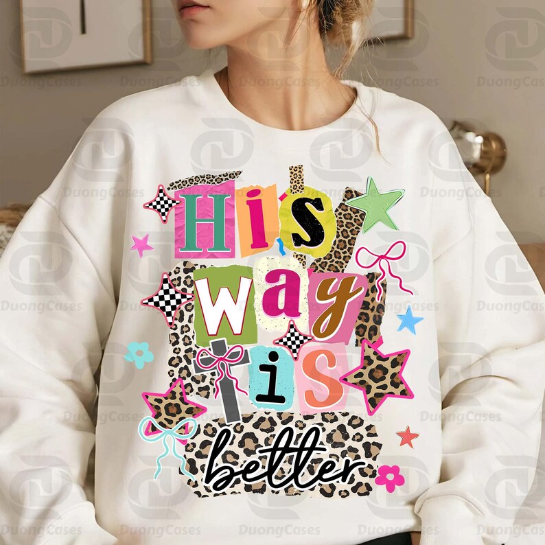 May include: White sweatshirt with the text "His way is better" in a colorful, patchwork design. The design includes stars, bows, and leopard print accents, creating a vibrant and eye-catching graphic.