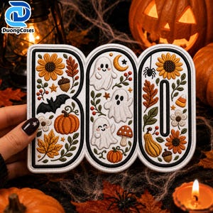 May include: An embroidered patch shaped like the word BOO, featuring white ghosts, orange pumpkins, yellow sunflowers, autumn leaves, a black bat, a spider, a crescent moon, and mushrooms, all outlined in black thread on a white fabric background.