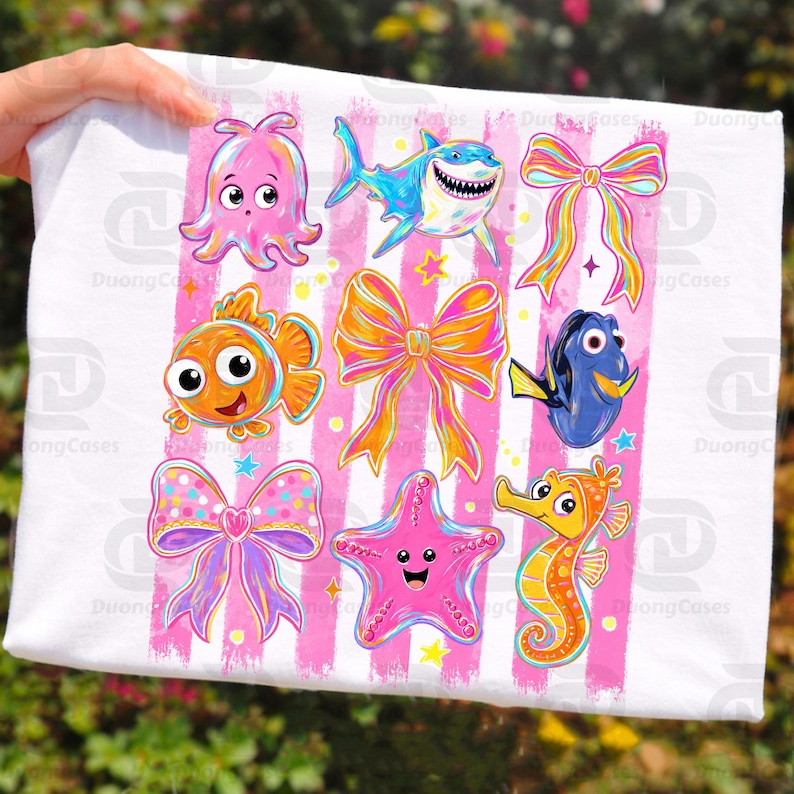 May include: White fabric featuring colorful cartoon sea creatures and bows on pink striped background. Includes an octopus, shark, clownfish, Dory, starfish, and seahorse. The design is playful and vibrant.