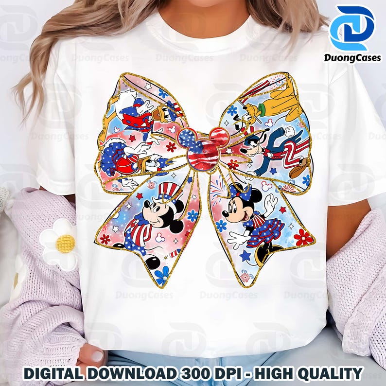 K&ouml;nnte beinhalten: Ein wei&szlig;es T-Shirt mit einem bunten Schleifendesign, das Mickey Mouse und andere Disney-Charaktere in patriotischer rot-wei&szlig;-blauer Kleidung zeigt. Die Schleife ist mit goldenem Glitzer und Sternen verziert.