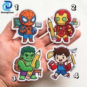 May include: Four embroidered patches featuring cartoon characters: Spider-Man with a book and chalkboard, Iron Man holding a pencil near alphabet blocks, the Hulk holding a large pencil, and a student with a book, ruler, and paper airplane.