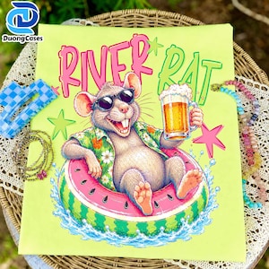 May include: A light green t-shirt featuring a graphic of a smiling rat wearing sunglasses and a floral shirt, floating in a watermelon inner tube while holding a beer mug. The text RIVER RAT is printed in pink and green above the illustration.