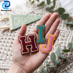 May include: Three embroidered varsity-style letter patches in the shapes of H, I, and J. The H is dark maroon with a gold border, the I is teal with an orange border, and the J is light pink with a yellow border. Each patch features a thick, textured thread finish.