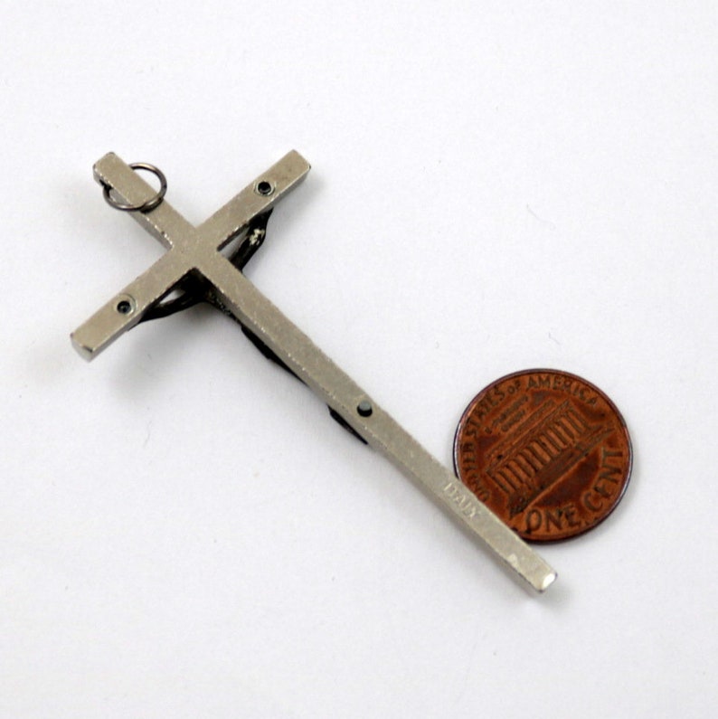 Puede incluir: Crucifijo de metal plateado con una peque&ntilde;a figura de Jesucristo. El crucifijo es aproximadamente del tama&ntilde;o de una moneda de un c&eacute;ntimo de euro.