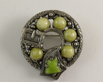 Può includere: Un fermaglio celtico in argento e verde con un designo decorativo e pietre verdi.