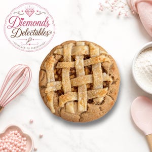 Pode incluir: Uma tarte de fruta redonda com uma crosta de rede dourada coberta com cristais de açúcar grossos. A tarte é rodeada por um batedor rosa, uma pequena taça com granulado rosa, uma taça com farinha branca e uma espátula de silicone rosa.
