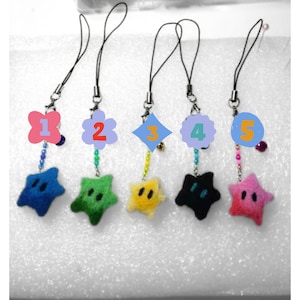 May include: Five colorful star-shaped plush keychains with different colored beads and charms. The stars are blue, green, yellow, black, and pink.