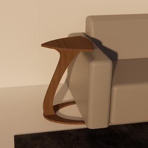 以下が含まれることがあります： ユニークな曲線デザインのモダンな木製サイドテーブル。テーブルは三角形の天板と、丸みを帯びたベースに曲がる単一の流れるような脚を備えています。木材は暖かく自然な仕上がりで、ニュートラルカラーのソファの隣に配置されています。