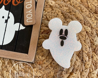 May include: White glitter ghost with black Mickey Mouse ears and eyes on a retractable badge reel. The ghost is attached to a clear plastic badge holder.
