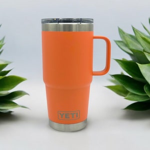 May include: Orange YETI Rambler 30 oz. travel mug with a stainless steel lid and handle.