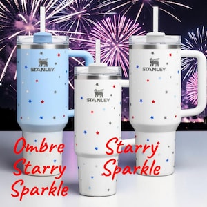 Pu&ograve; includere: Tre bicchieri isolati Stanley con coperchi e cannucce. Uno &egrave; azzurro con stelle rosse, bianche e blu. Gli altri due sono bianchi con stelle rosse, bianche e blu. Il testo "Ombre Starry Sparkle" e "Starry Sparkle" &egrave; scritto sui bicchieri.