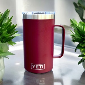 K&ouml;nnte beinhalten: Eine burgunderrote YETI Rambler 14 oz Tasse mit einem Edelstahldeckel und einem Griff.