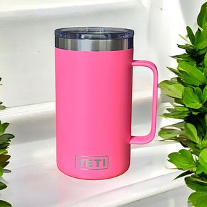 K&ouml;nnte beinhalten: Eine rosa YETI Rambler 14 oz Tasse mit einem Edelstahldeckel und einem Griff.