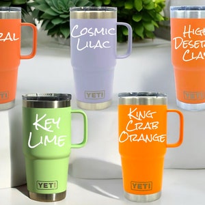 May include: Five YETI Rambler Tumblers with different colored lids and handwritten names on the side: Coral, Cosmic Lilac, High Desert Clay, Key Lime, and King Crab Orange.