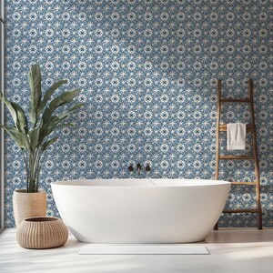 May include: A modern bathroom with a white oval bathtub, a wooden ladder with a white towel, and a large potted plant. The wall is covered in a blue and white patterned wallpaper. A woven basket sits near the tub.